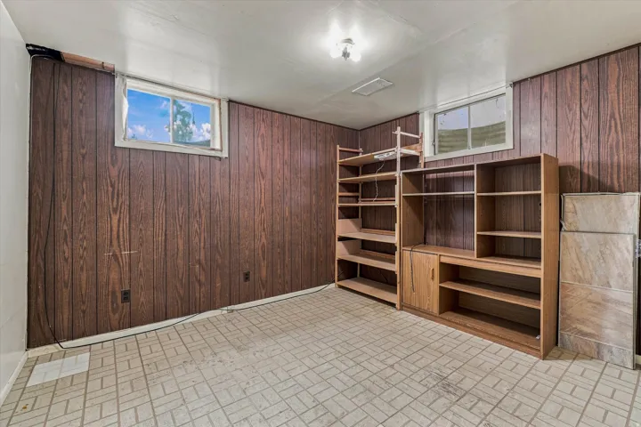 Wood-paneled walls with two windows and tile flooring