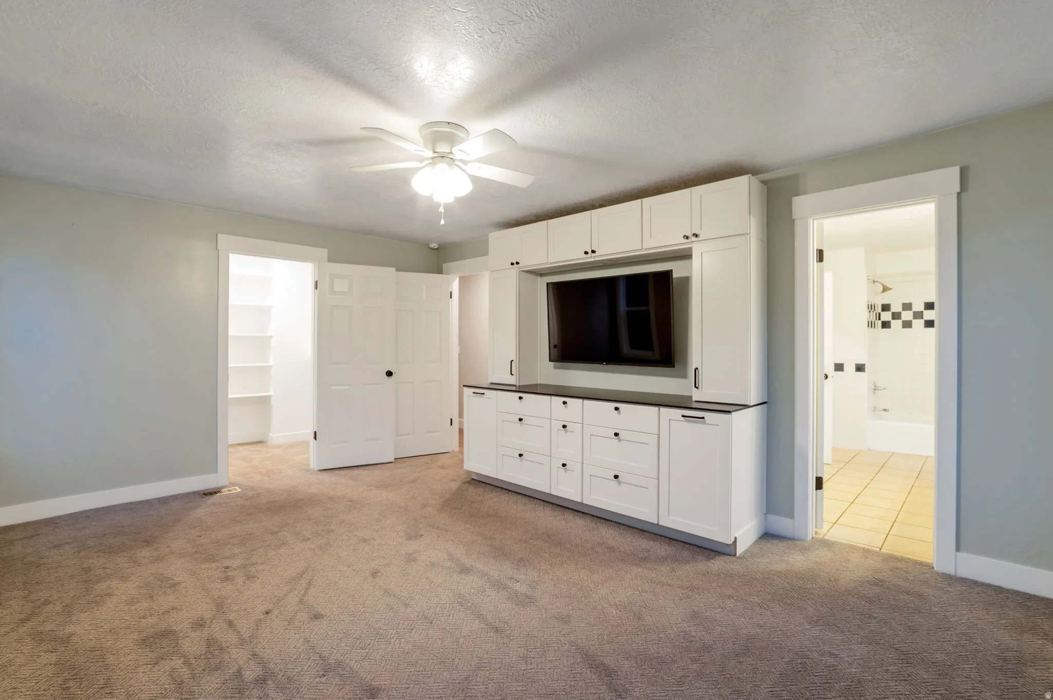 Master bedroom built-in media center with white cabinetry and dark countertops