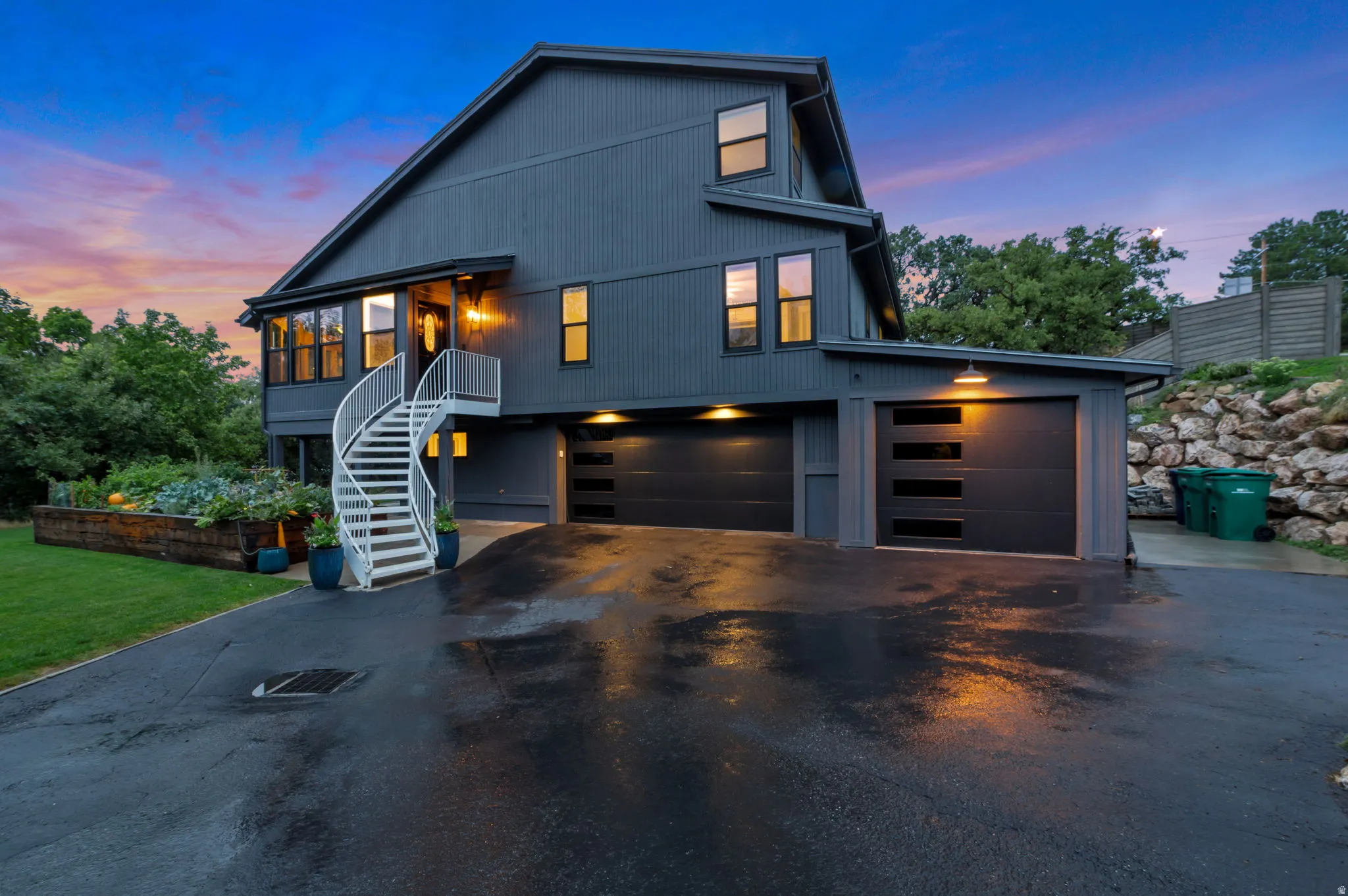 Contemporary exterior featuring dark horizontal siding and multiple windows. Three car garage, large driveway and multiple parking spots allows for cars, guests and toys!
