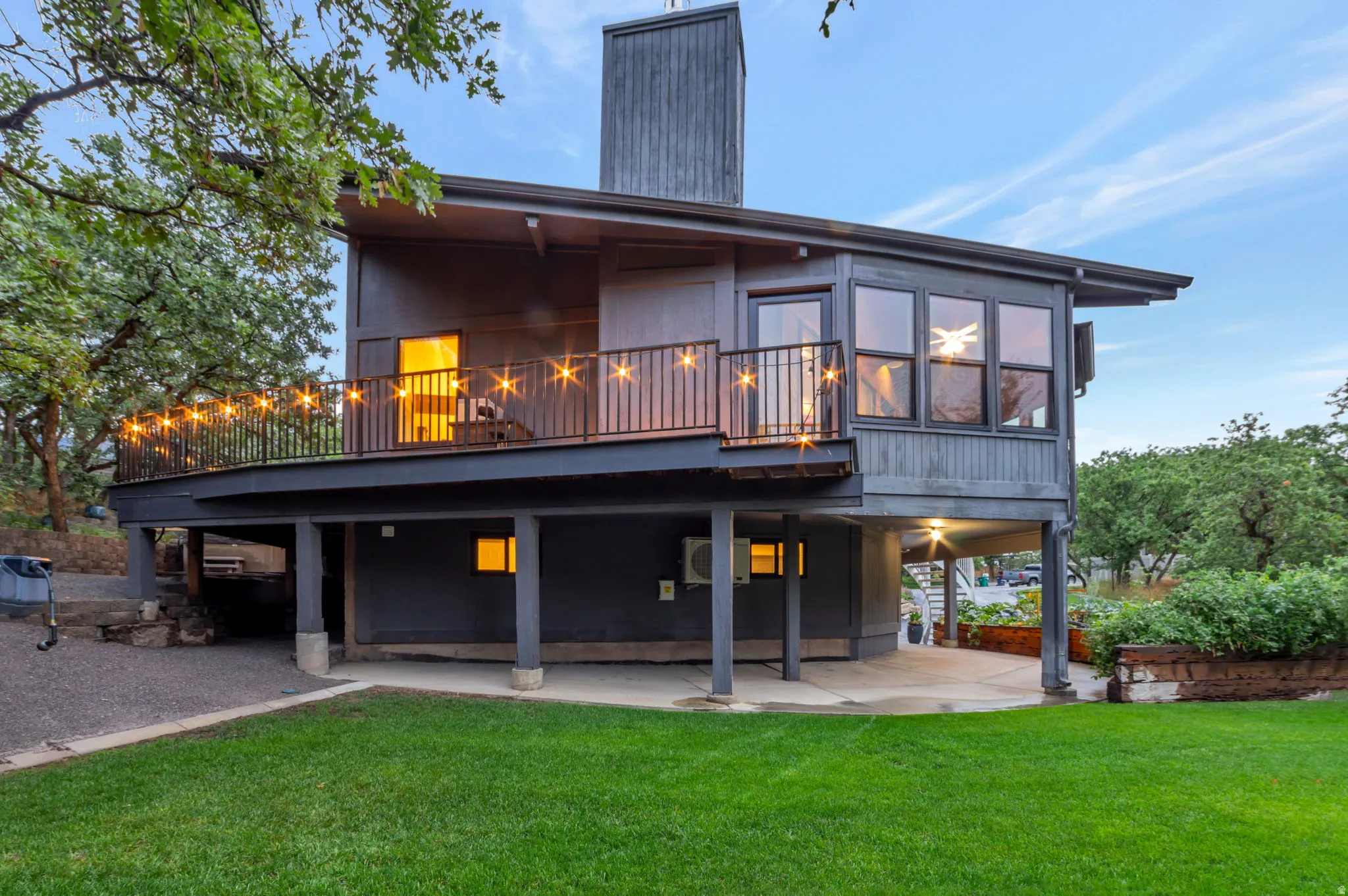 Multi-level exterior with a large second-story deck, multiple large windows, and a ground-level patio