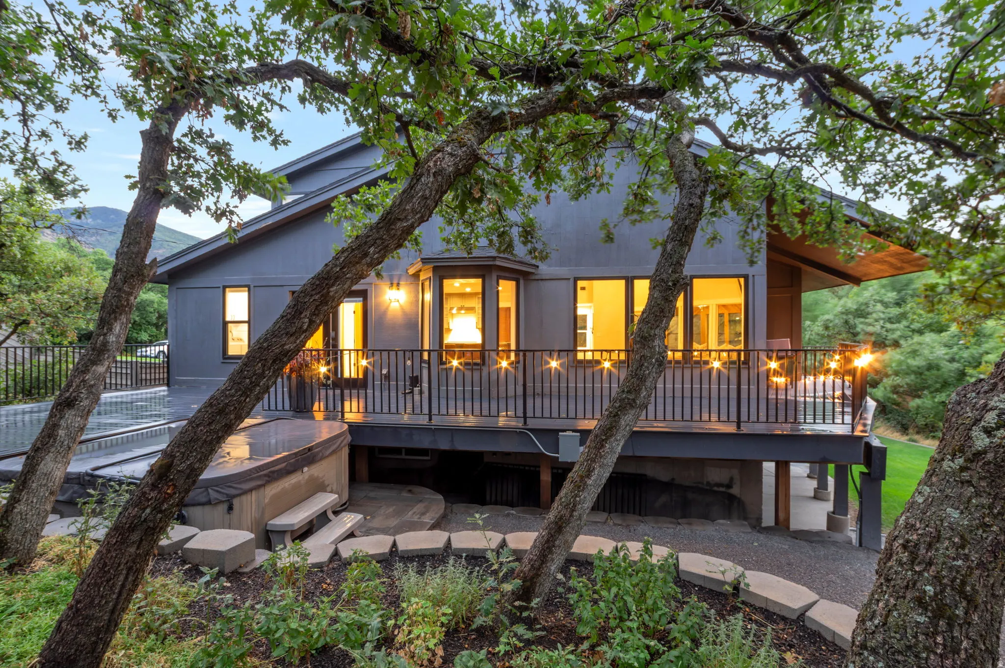 Contemporary exterior with a spacious deck, integrated spa, and mature landscaping. Enjoy anytime of day in the privacy of this backyard oasis.