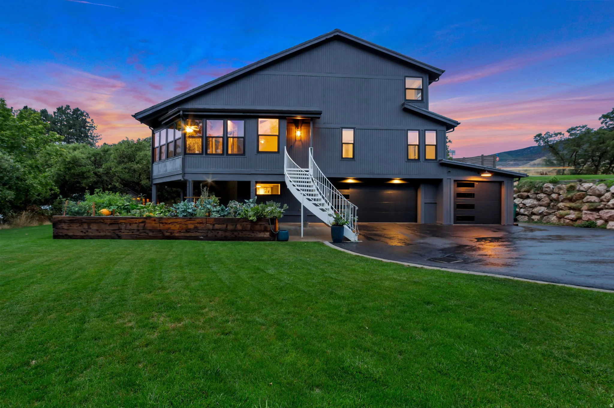Contemporary exterior with dark siding, multiple garage bays, and a spiral staircase