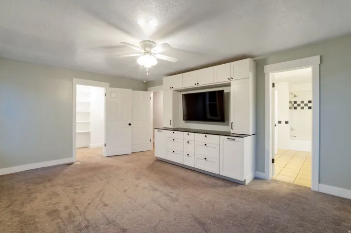 Master bedroom built-in media center with white cabinetry and dark countertops