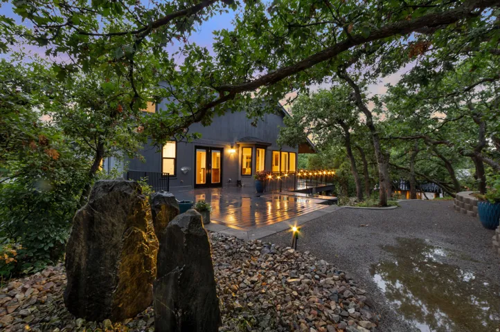 Expansive outdoor deck with string lighting, beautiful natural stone fountain surrounded by mature trees