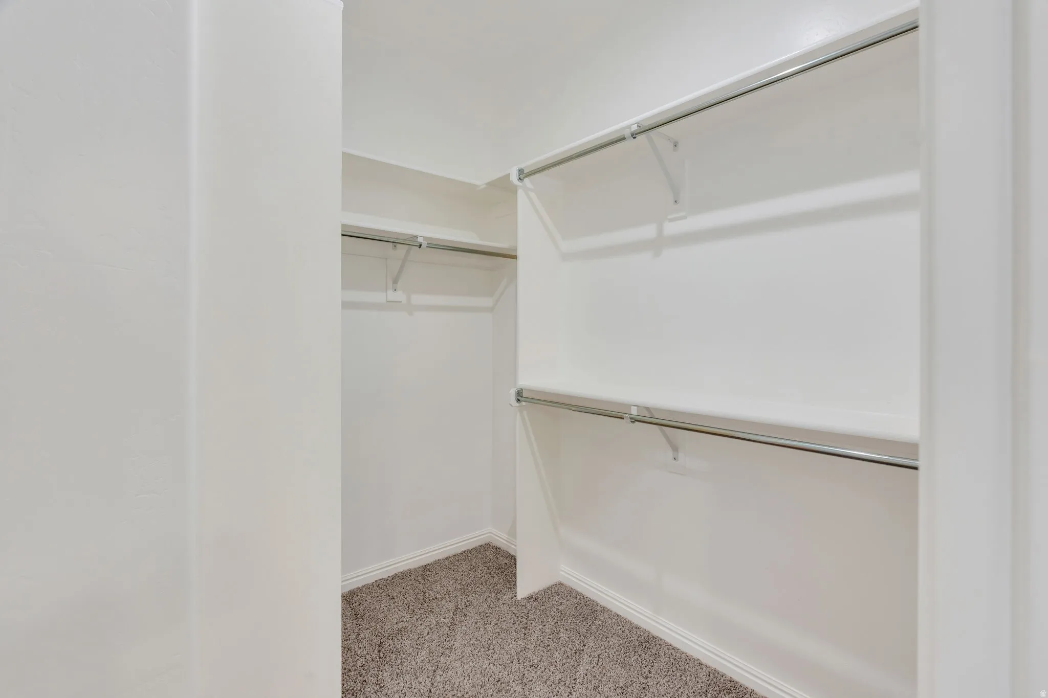 Wall-to-wall carpeting with multiple shelving units and clothing rods