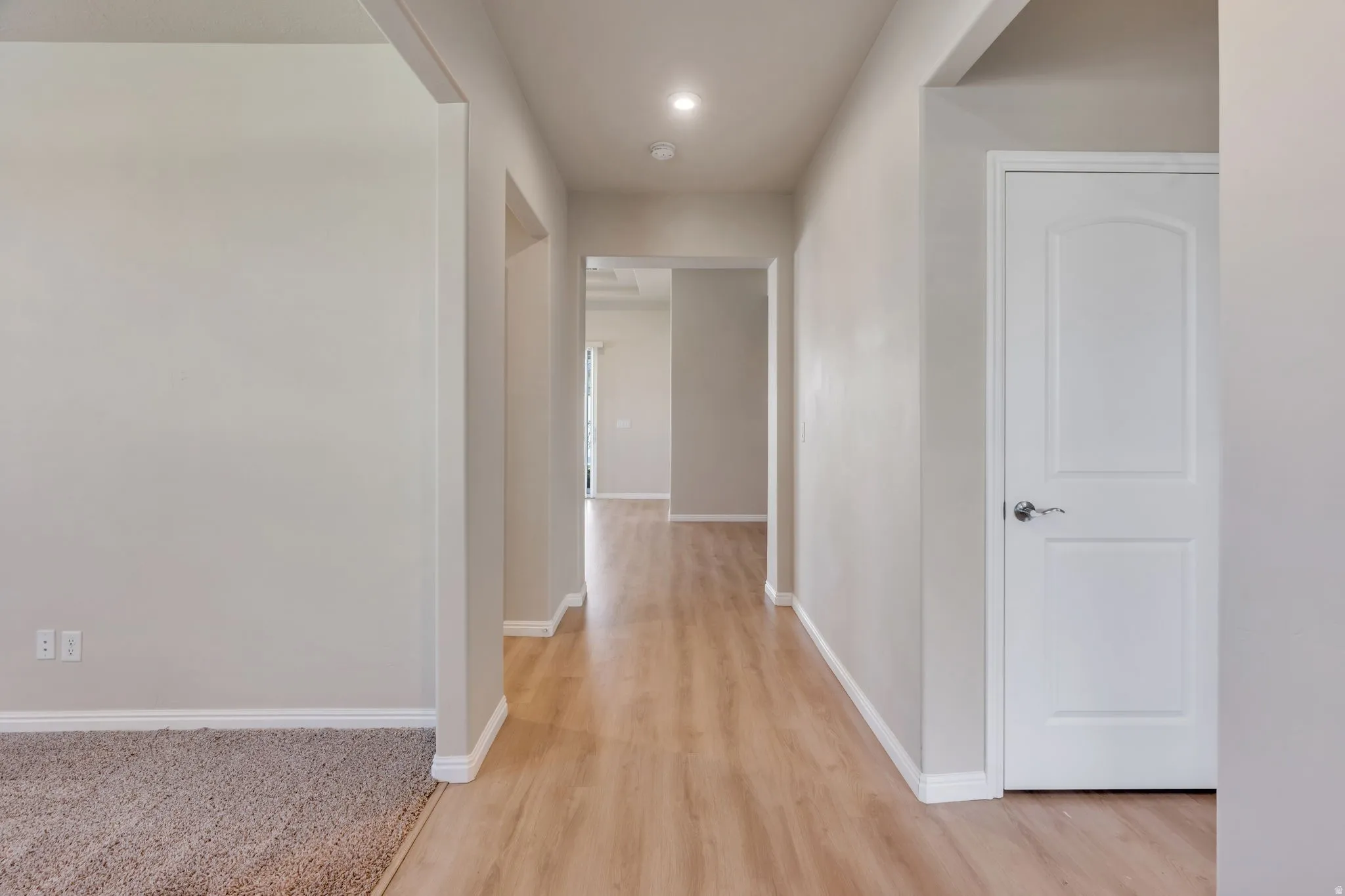 Hallway featuring wood-finish flooring, recessed lighting, and a white interior door