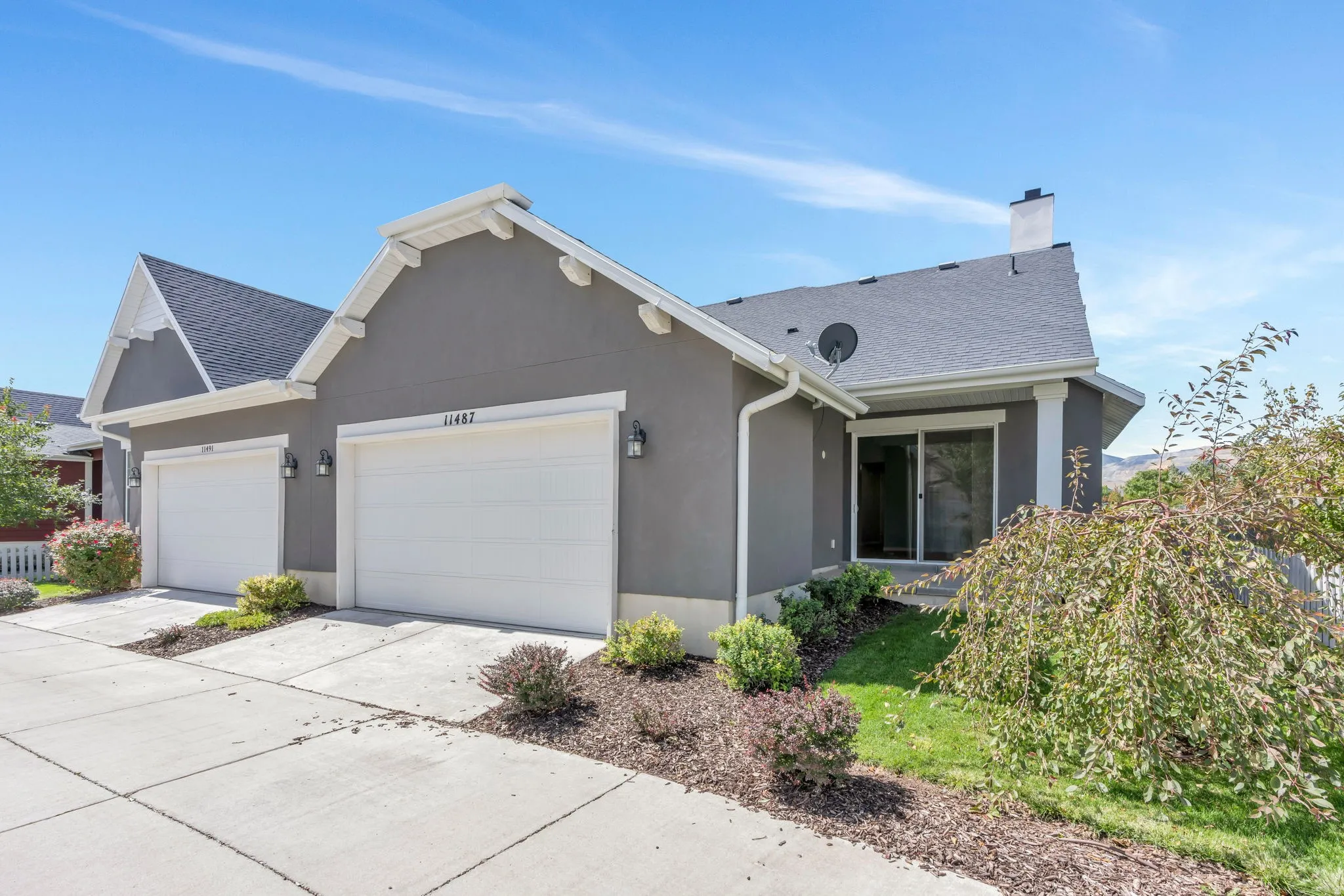 Stucco exterior with white trim, dual garage doors, and a sliding glass door
