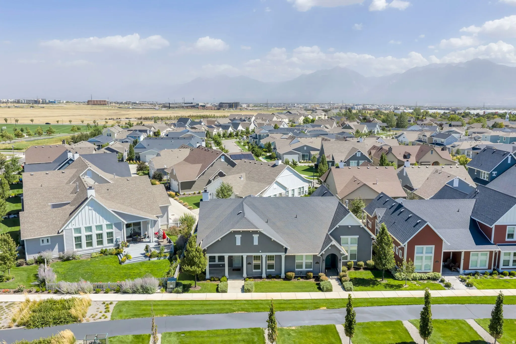 Expansive residential neighborhood with varied architectural styles, mature landscaping, paved roadways, and distant mountain scenery