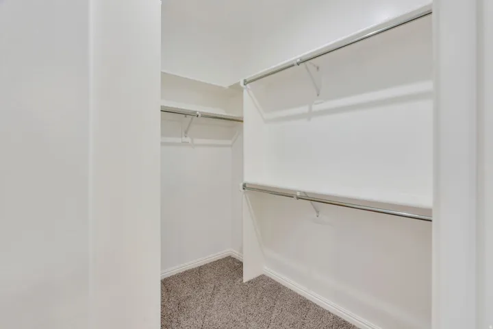 Wall-to-wall carpeting with multiple shelving units and clothing rods