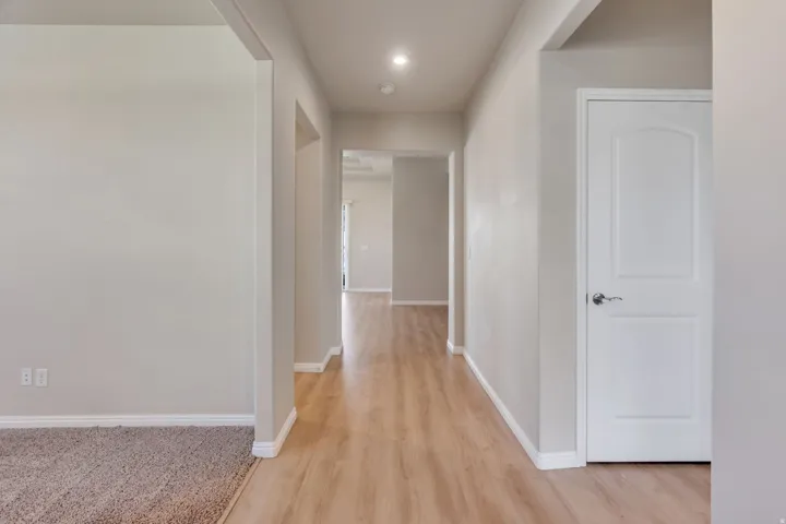 Hallway featuring wood-finish flooring, recessed lighting, and a white interior door