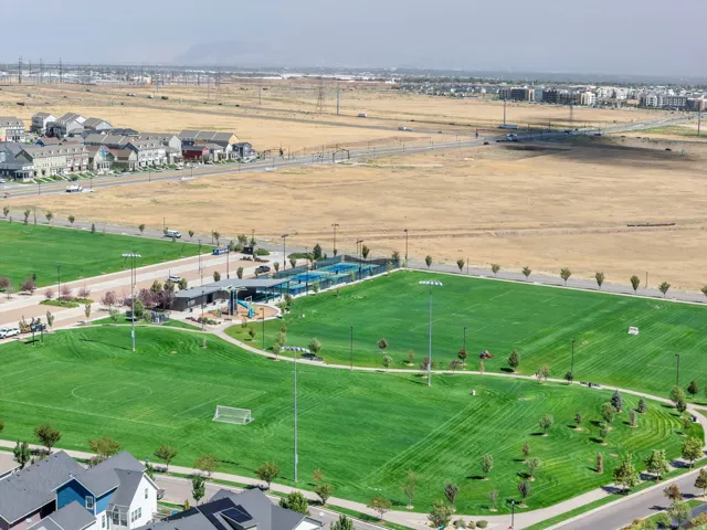 Expansive green space featuring multiple sports fields, paved pathways, and a playground structure