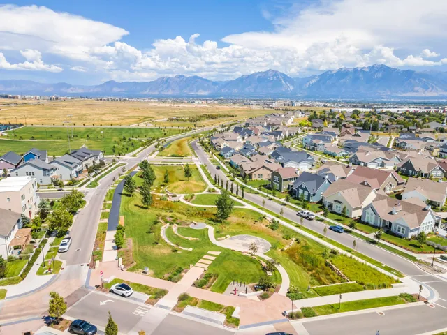 Residential neighborhood with a community park, streets, and sidewalks, set against a mountain backdrop