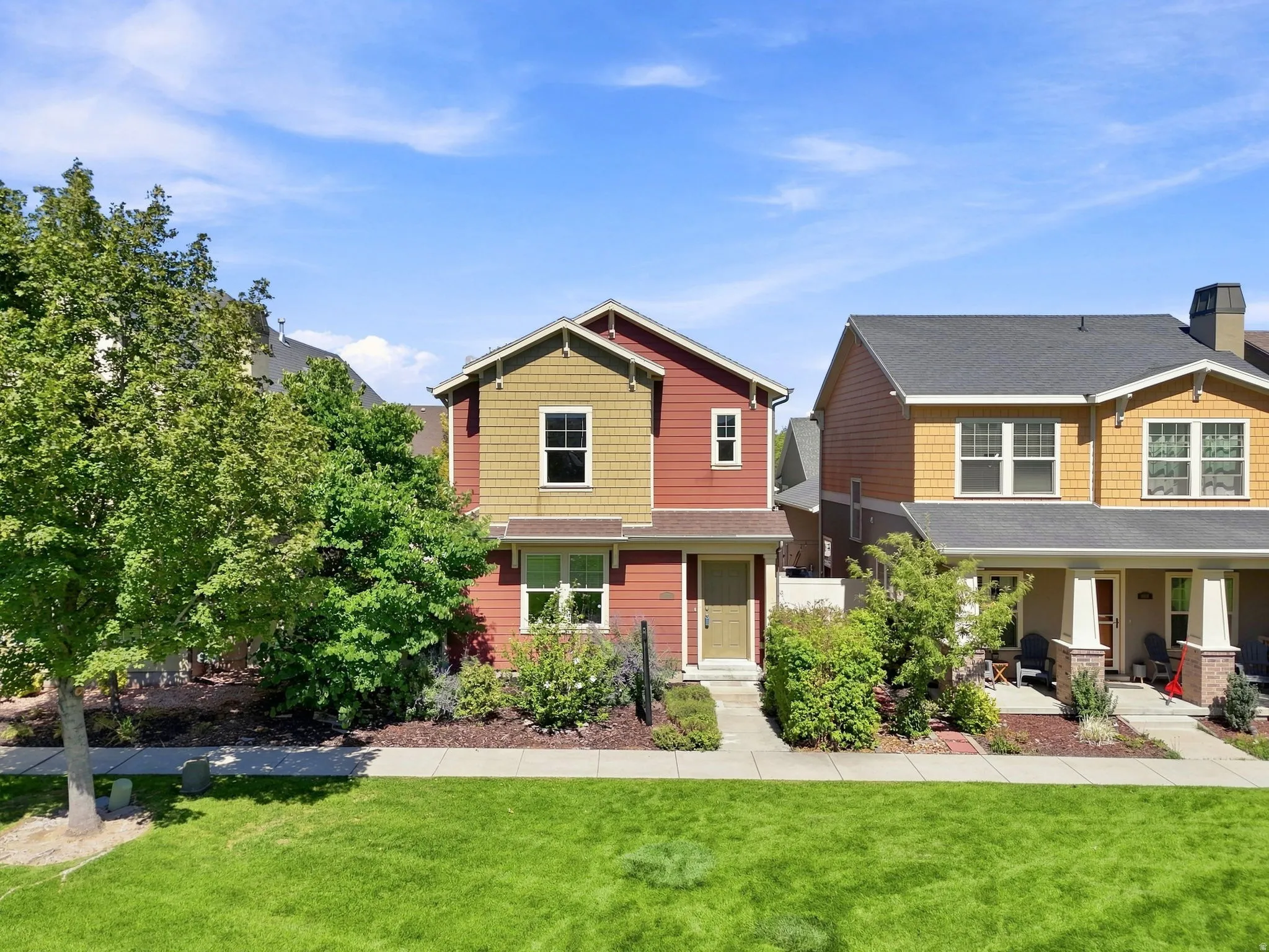 Two-story property featuring red siding and yellow shake siding accents, with a contrasting entry door
