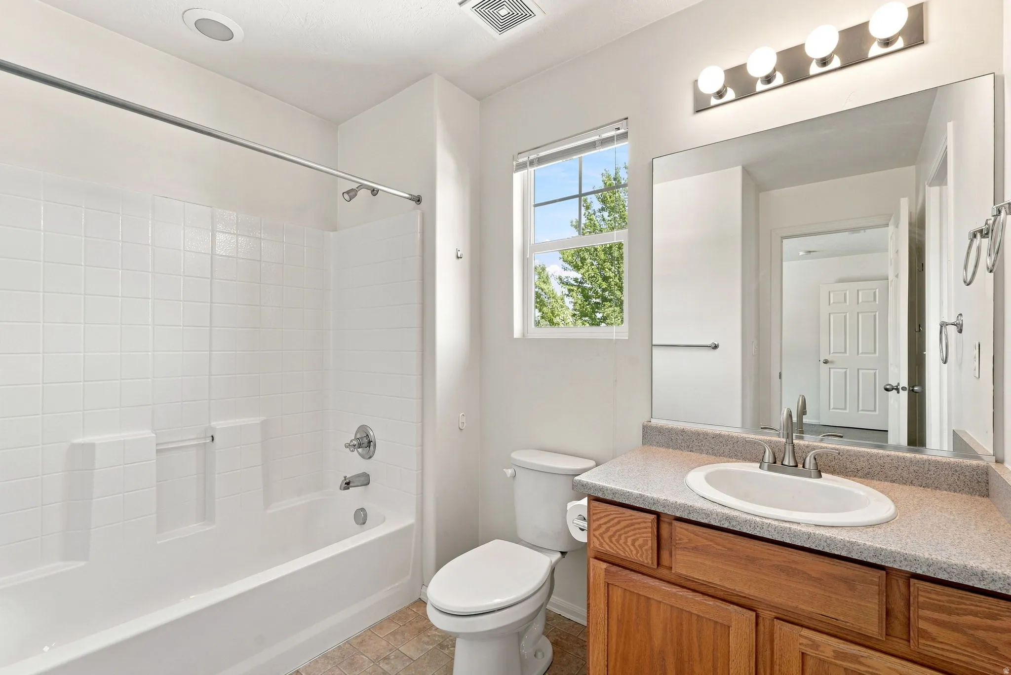 White tiled tub and shower combination with chrome fixtures