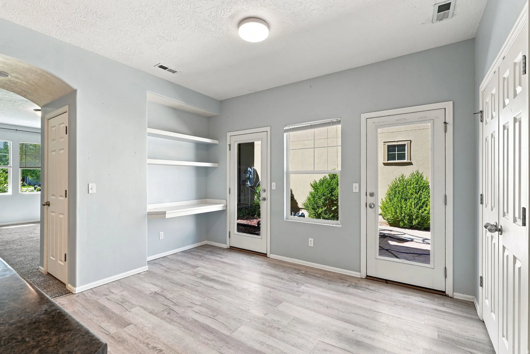 Light wood-finish flooring, built-in shelving with desk, two panel doors, and two exterior access doors