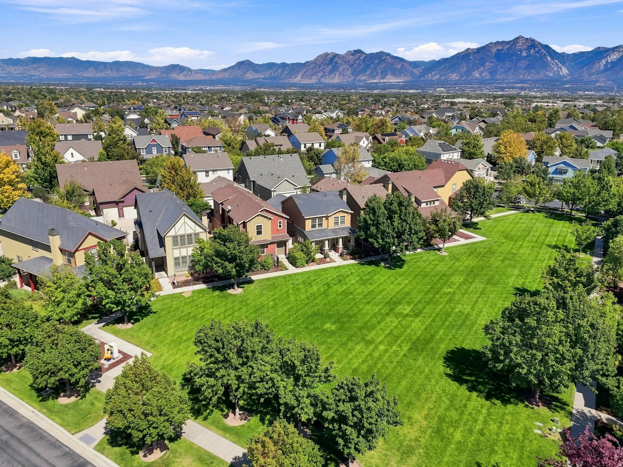 Expansive green space featuring mature trees and mountain backdrop
