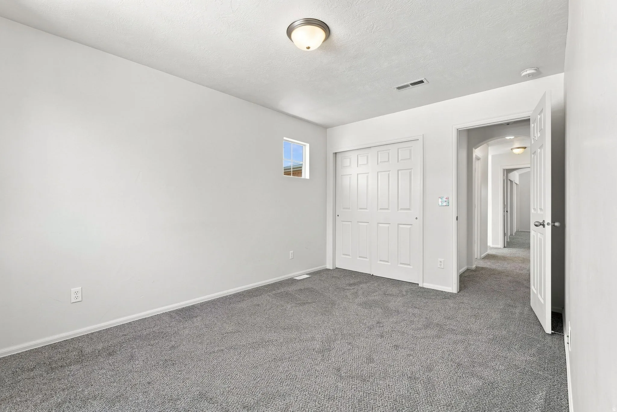 Neutral wall paint, gray carpet flooring, recessed window, bi-fold panel closet doors, and overhead ceiling light fixture