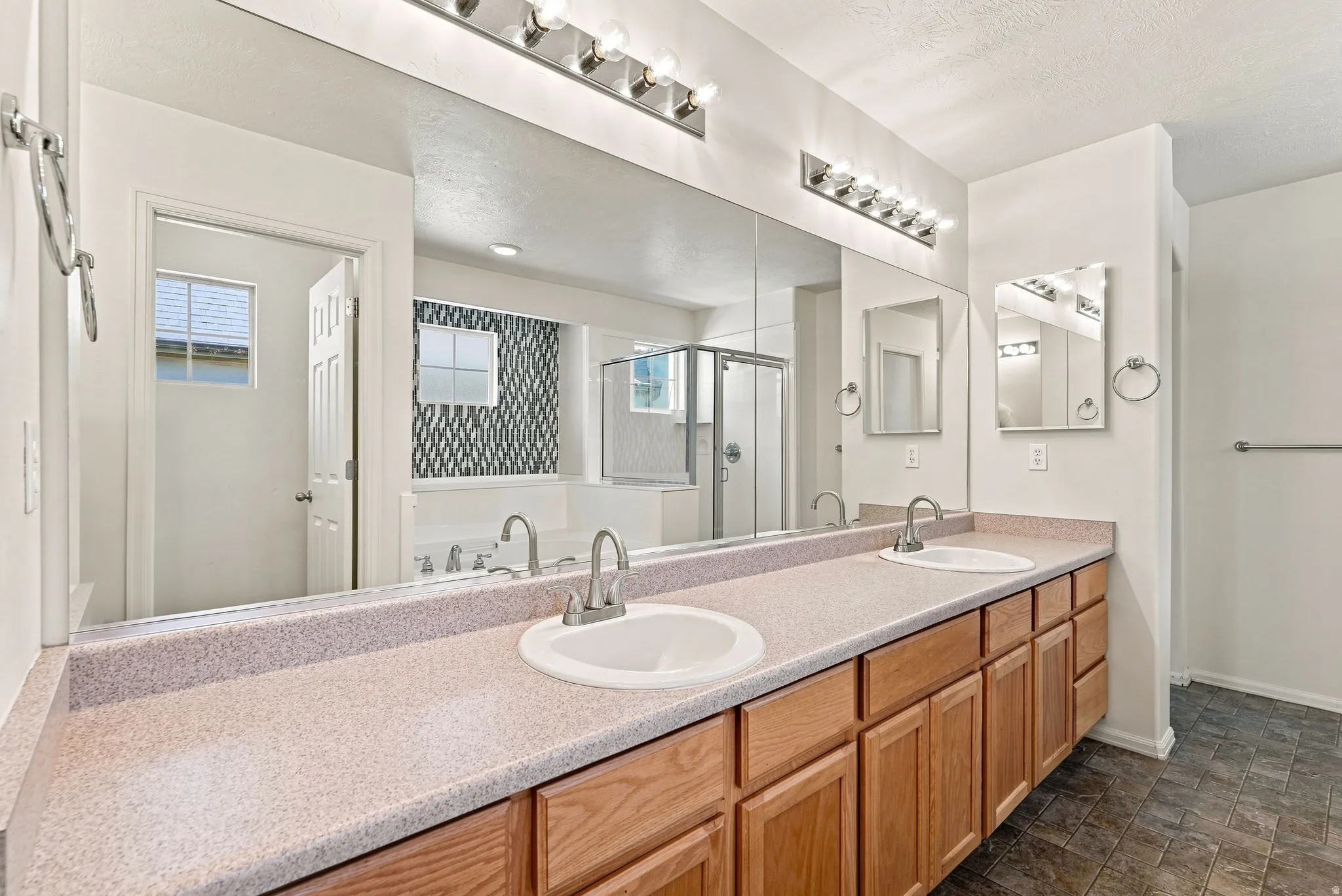 Double vanity with integrated sinks, oak-finish cabinetry, and a full-width mirror