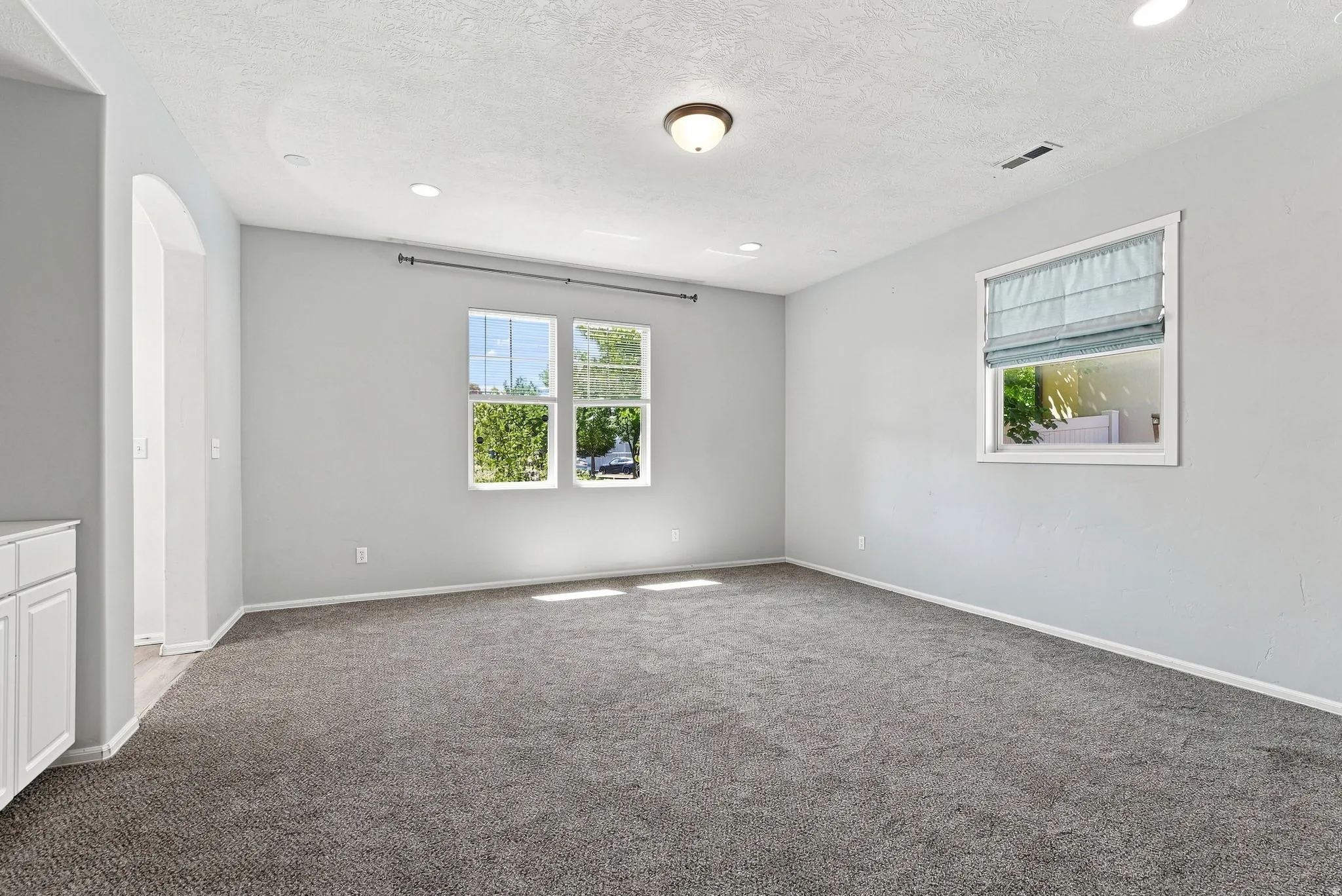 Recessed lighting, plush carpeting, arched doorway, and white cabinetry