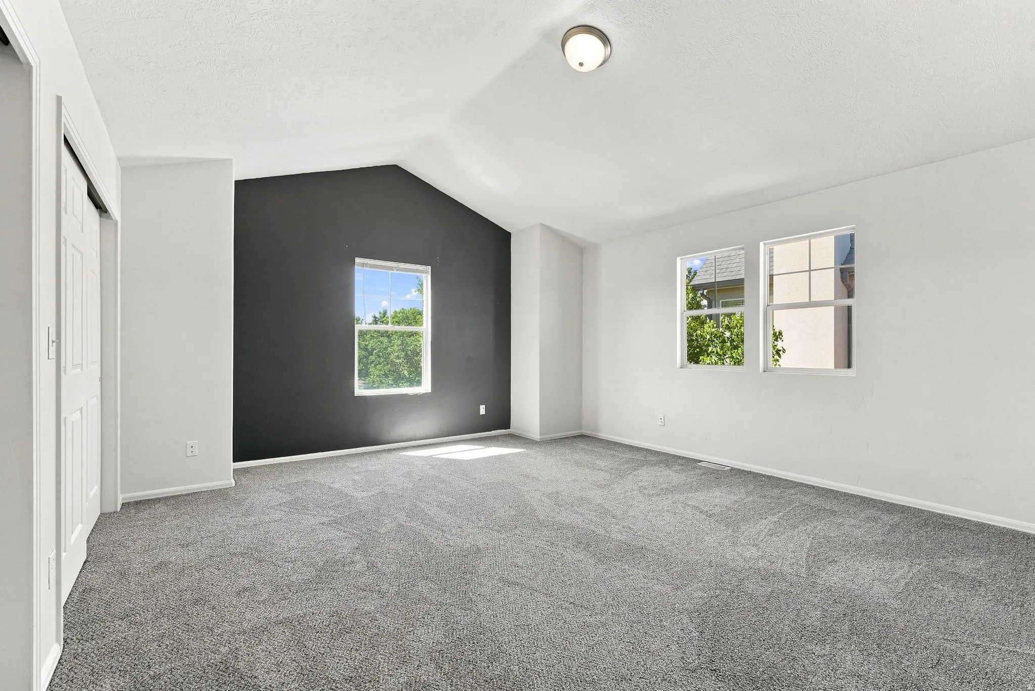 Vaulted ceiling, two windows, wall-to-wall carpeting, and a built-in closet with sliding doors