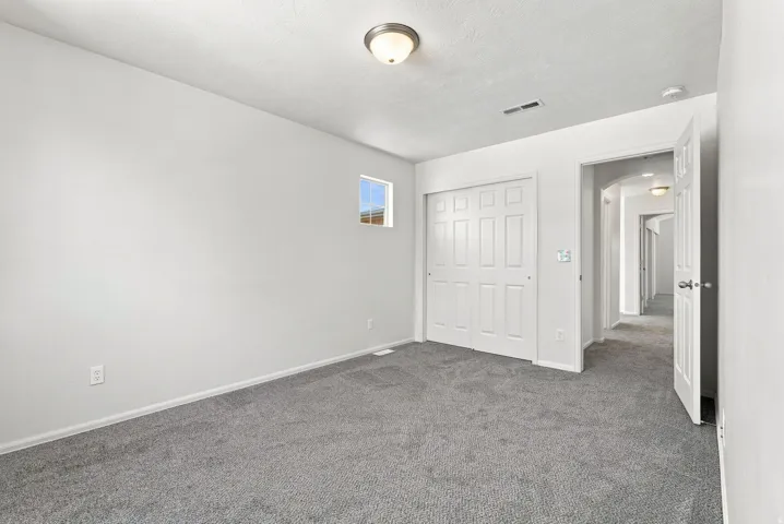 Neutral wall paint, gray carpet flooring, recessed window, bi-fold panel closet doors, and overhead ceiling light fixture