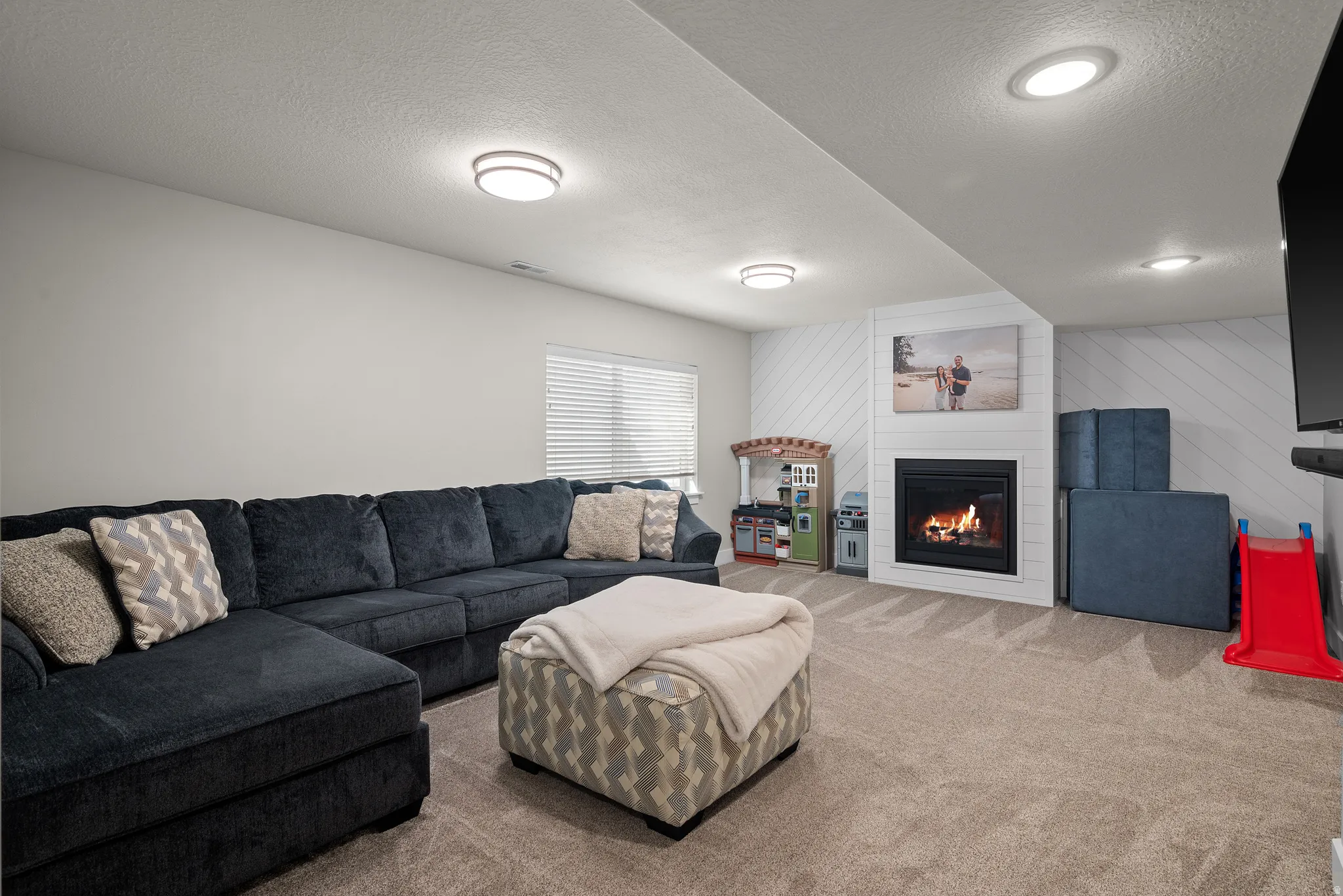 Built-in fireplace with a white shiplap surround, recessed lighting, carpet flooring, and a window with blinds