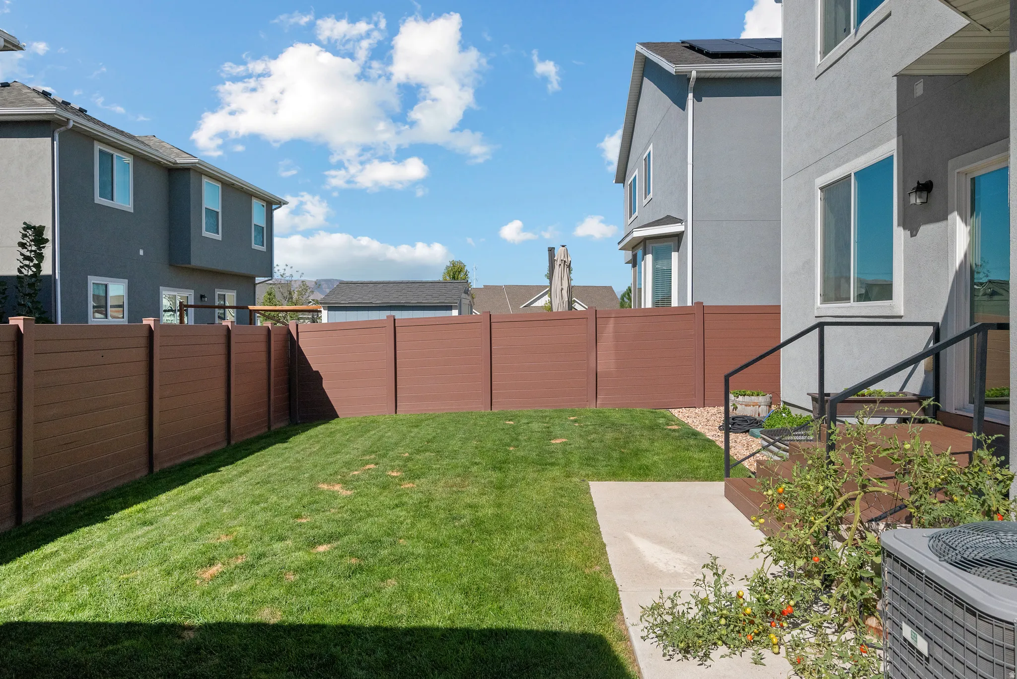 Rear exterior featuring a brown privacy fence, a concrete patio, and an air conditioning unit