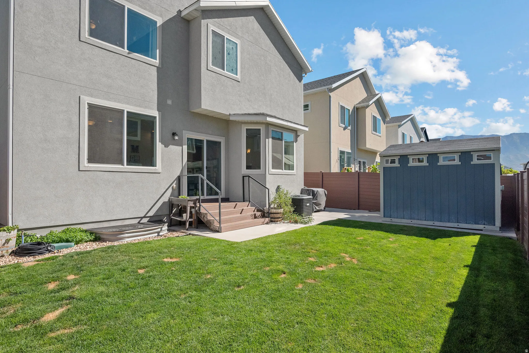 Rear exterior with stucco siding, sliding glass door, and a ground-level patio