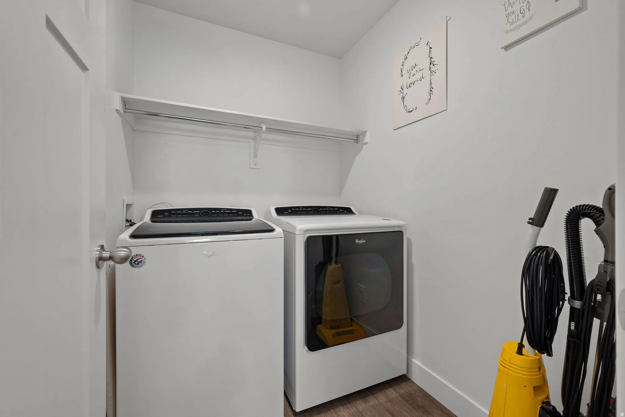 Laundry area featuring a built-in shelving unit, wood-finish flooring, and white walls