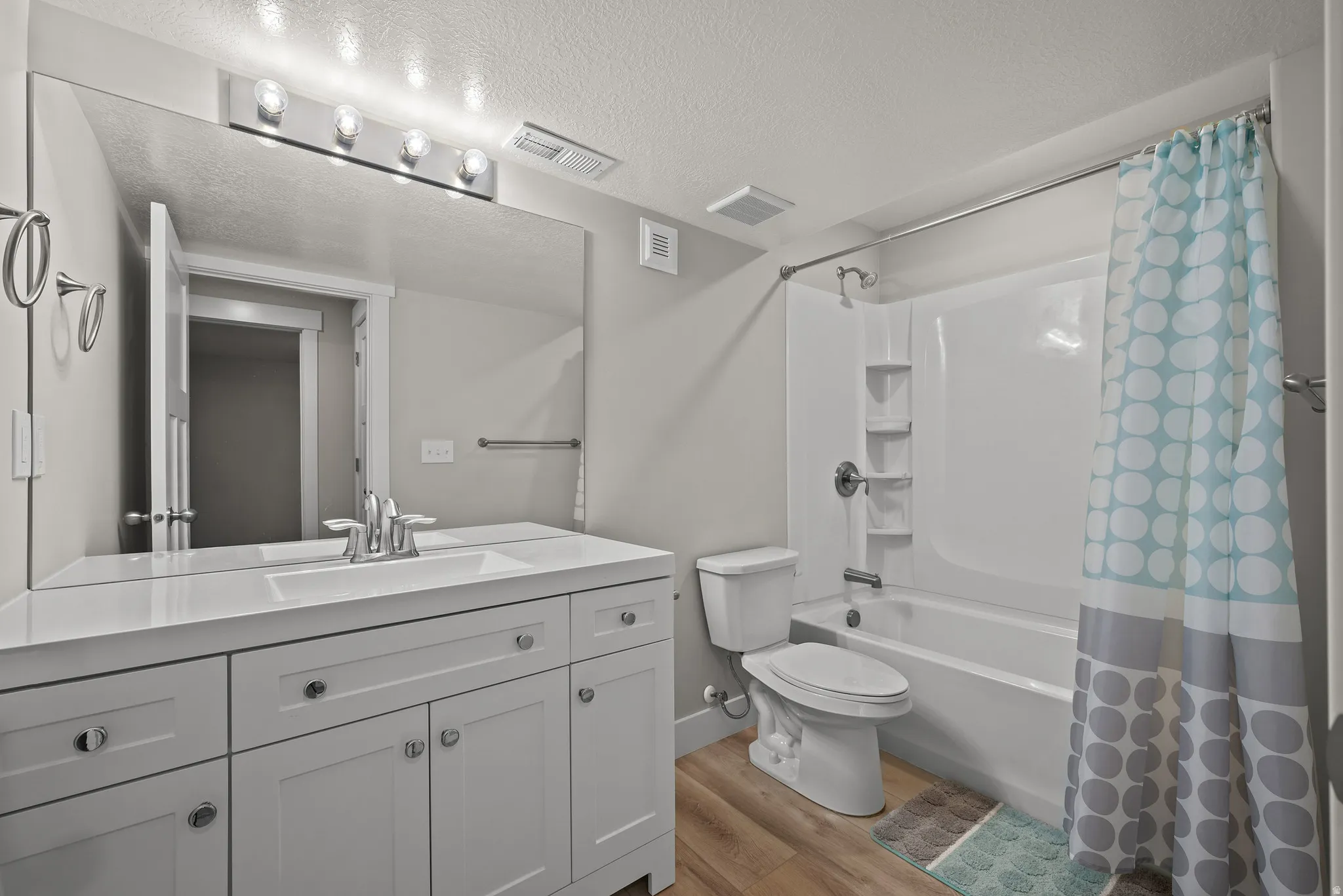 White vanity with integrated sink, chrome faucet, and expansive wall mirror