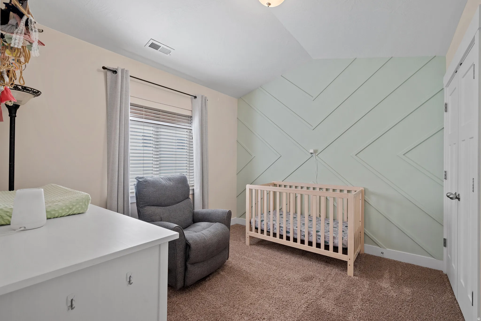 Accent wall with chevron paneling, neutral wall paint, window with blinds, and white trim