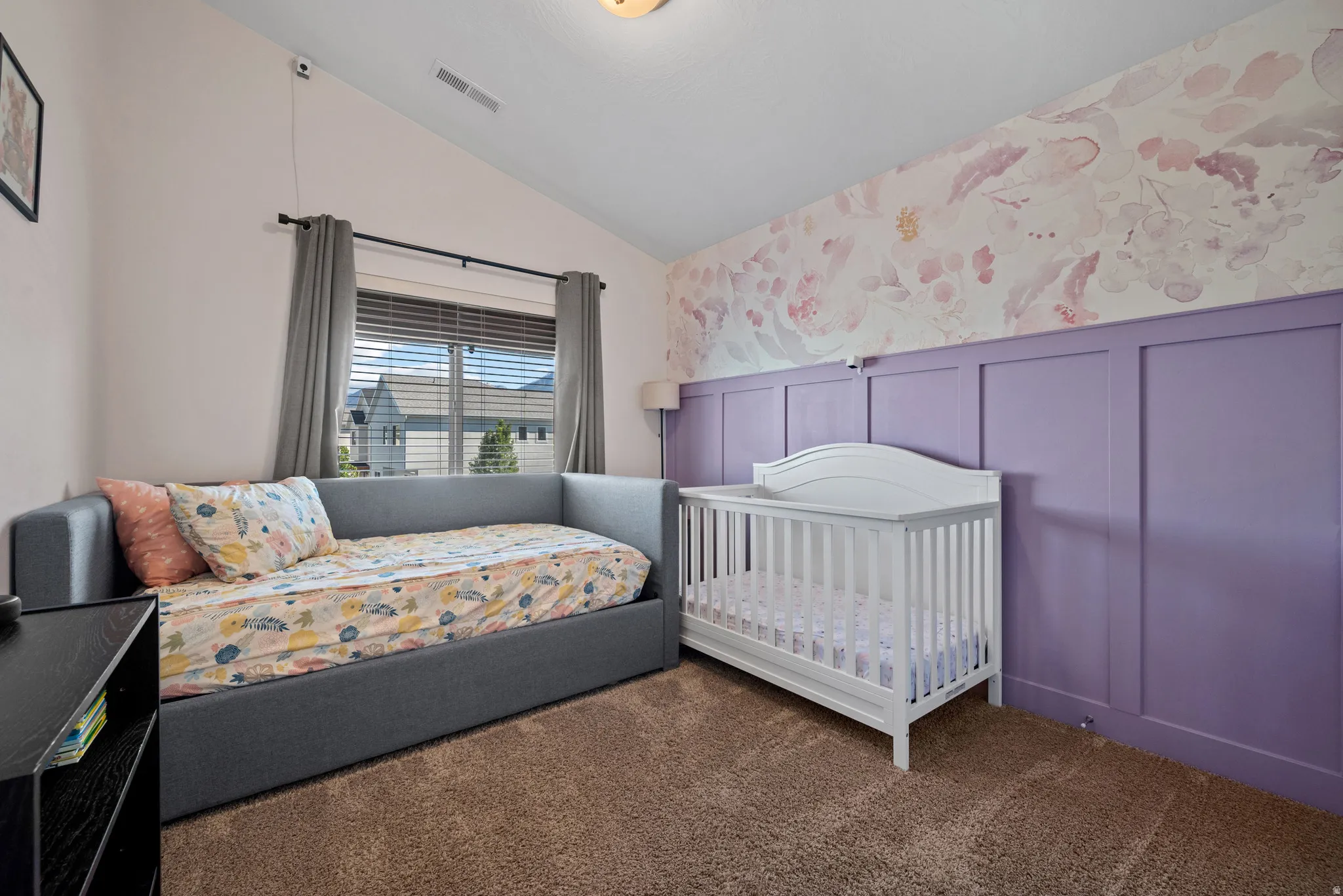 Vaulted ceiling, textured carpeting, window with blinds, decorative accent wall, and wainscoting
