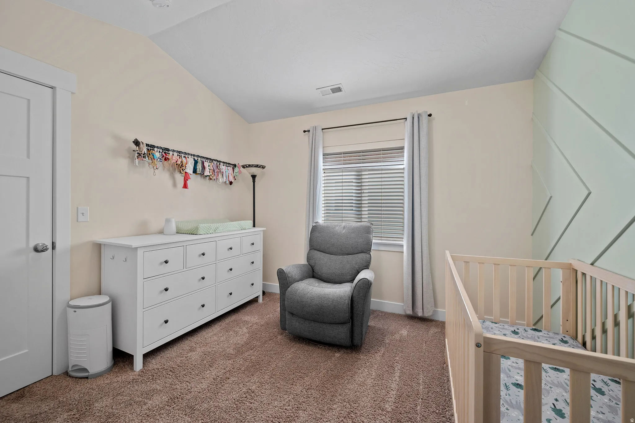 Vaulted ceiling with angled wood accent wall, neutral wall color, and window with blinds