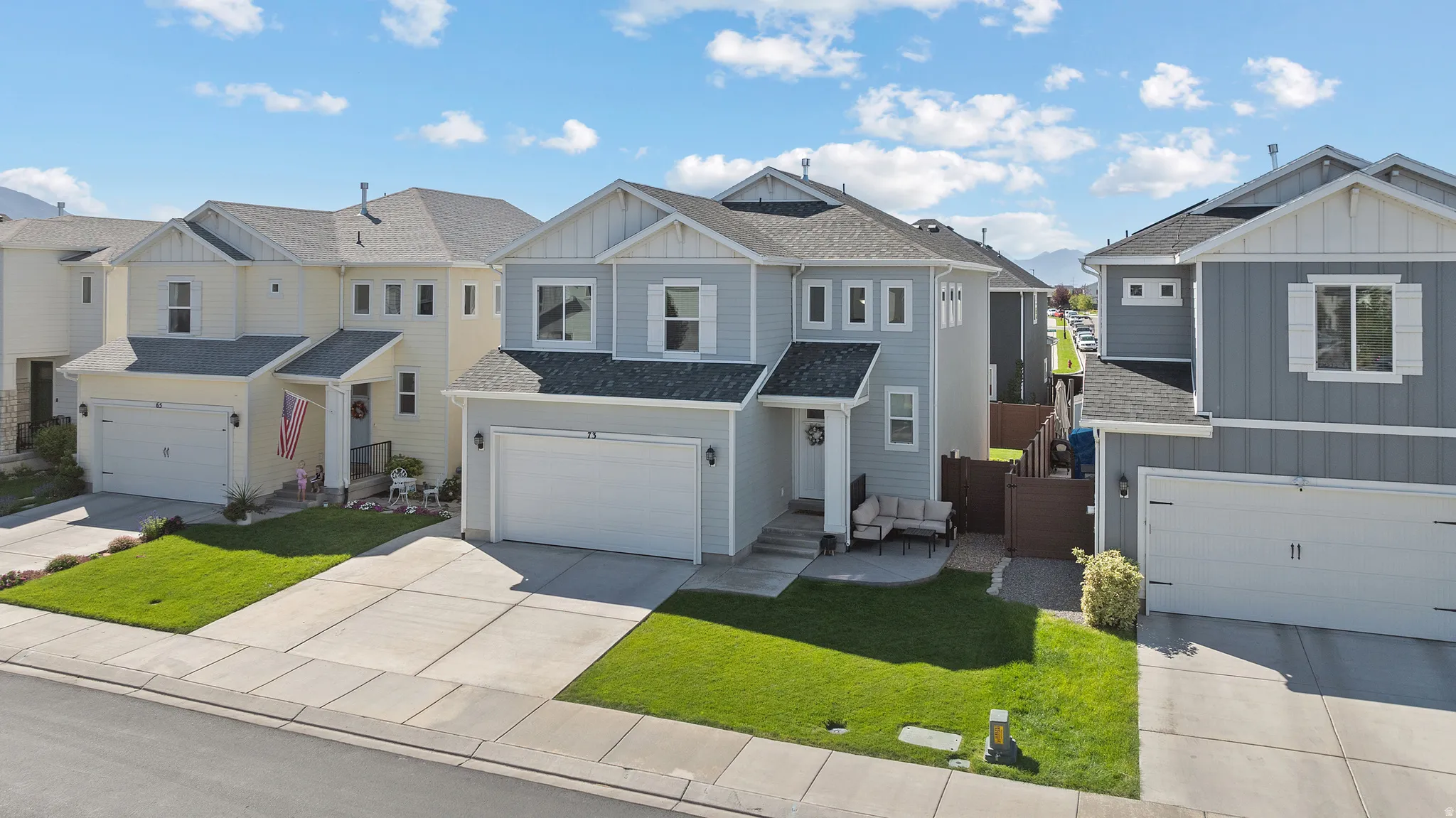 Two-story residence with a light gray facade, attached garage, and a covered porch