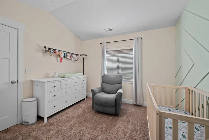 Vaulted ceiling with angled wood accent wall, neutral wall color, and window with blinds