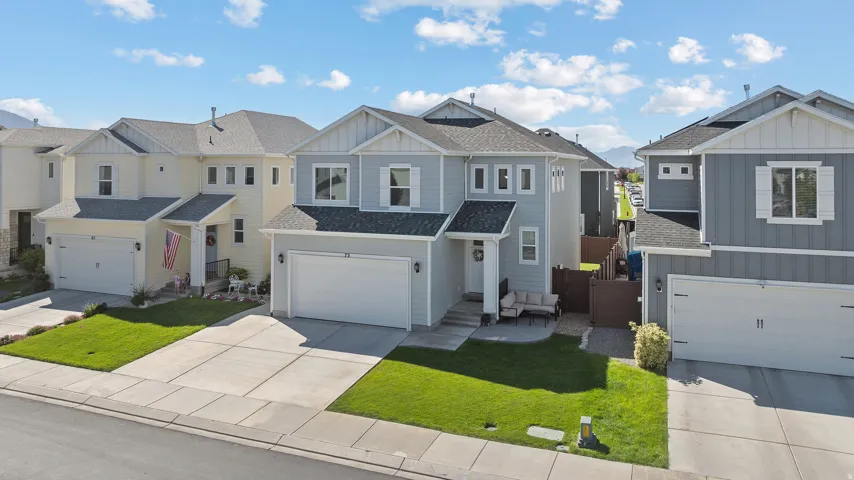 Two-story residence with a light gray facade, attached garage, and a covered porch