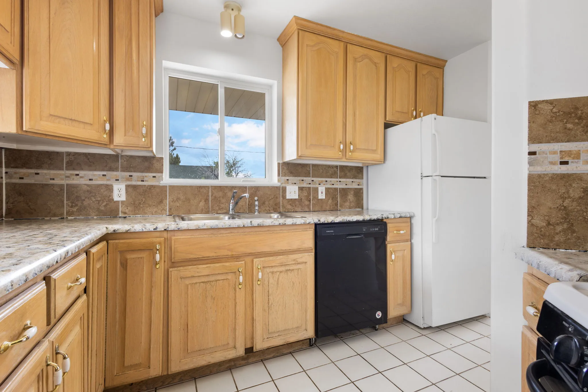 Wood-finish cabinetry, tile backsplash with decorative accent, laminate countertops, and white square tile flooring