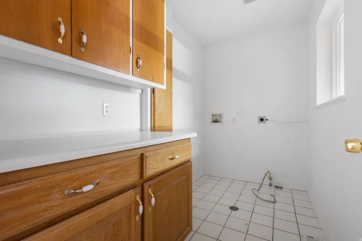 White tile flooring, wood-finish cabinetry, white countertops, built-in window, and overhead lighting