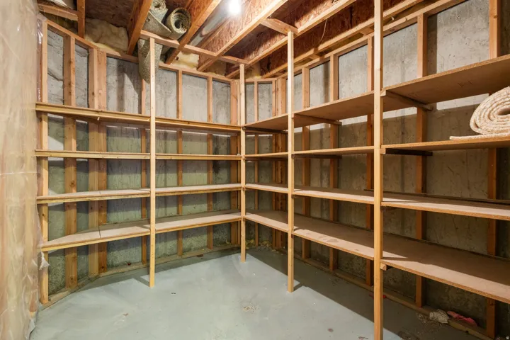 Extensive built-in shelving, exposed wood framing, concrete flooring, and overhead lighting