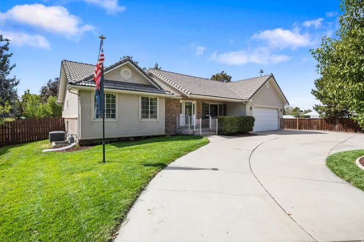 Stucco exterior with a tiled roof, attached garage, concrete driveway, and a fenced yard