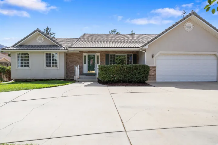 Stucco and brick exterior with a tiled roof, integrated two-car garage, and a concrete driveway