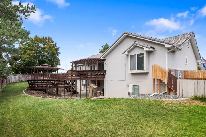 Expansive exterior featuring a multi-level wooden deck with a gazebo, stucco siding, and a tiled roof