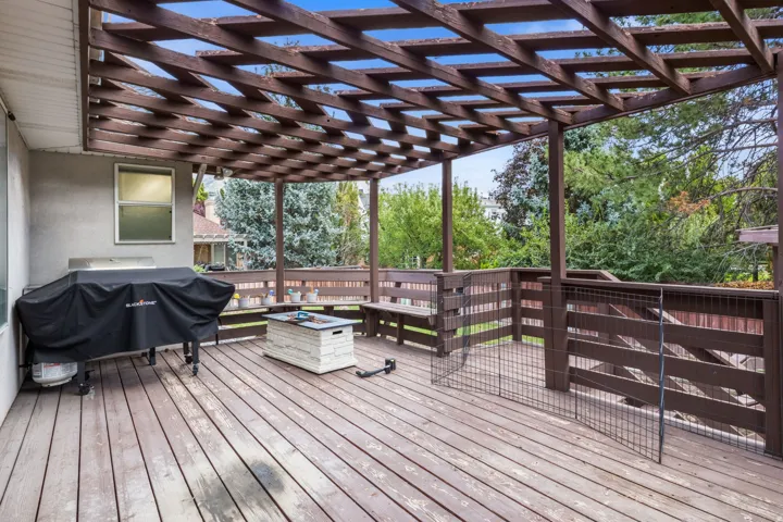 Expansive wood deck with a slatted pergola, integrating a permanent wooden bench