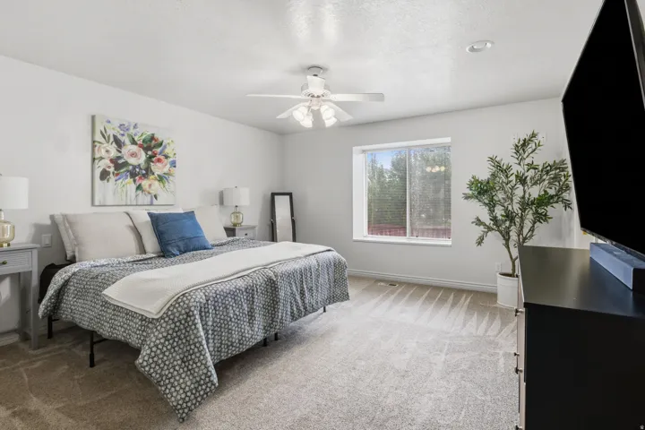 Wall-to-wall carpeted flooring, window with white trim, ceiling fan with integrated lighting, recessed ceiling light, and light gray wall paint
