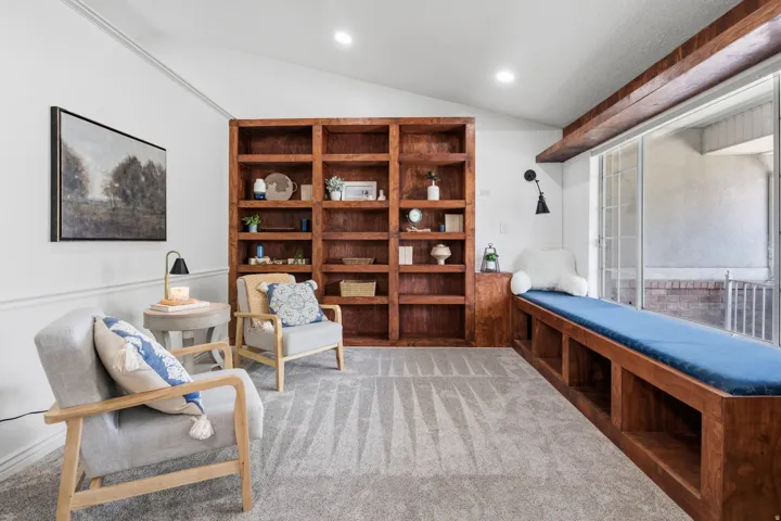 Vaulted ceiling, built-in wooden shelving, built-in window seating with storage, and recessed lighting