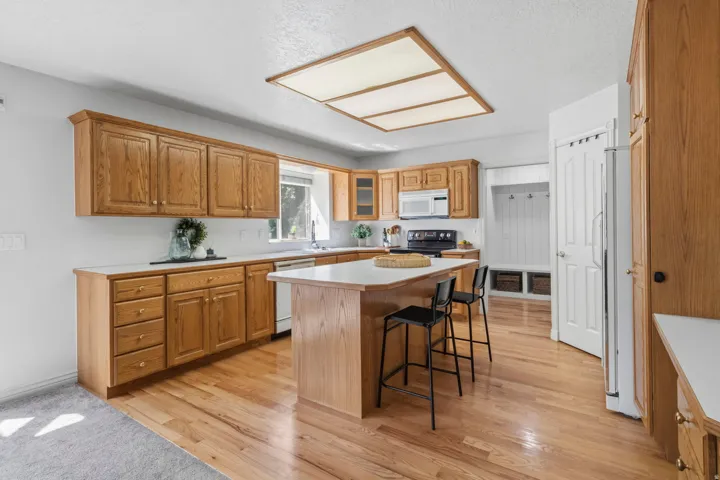 Kitchen featuring wood-finish cabinetry, white countertops, a central island, and wood-finish flooring