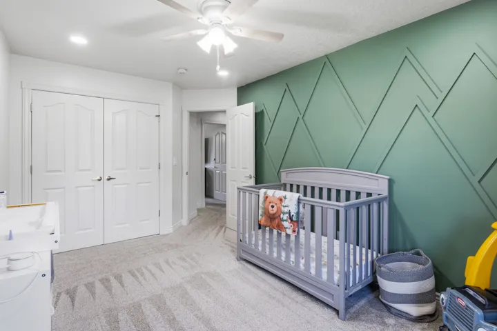 Textured accent wall, ceiling fan with integrated lighting, recessed ceiling lighting, light-toned carpeting, and double panel doors