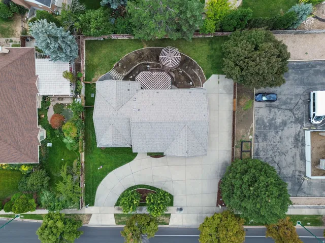 Property featuring a light-colored shingle roof, a curving concrete driveway, and a fenced backyard with a gazebo