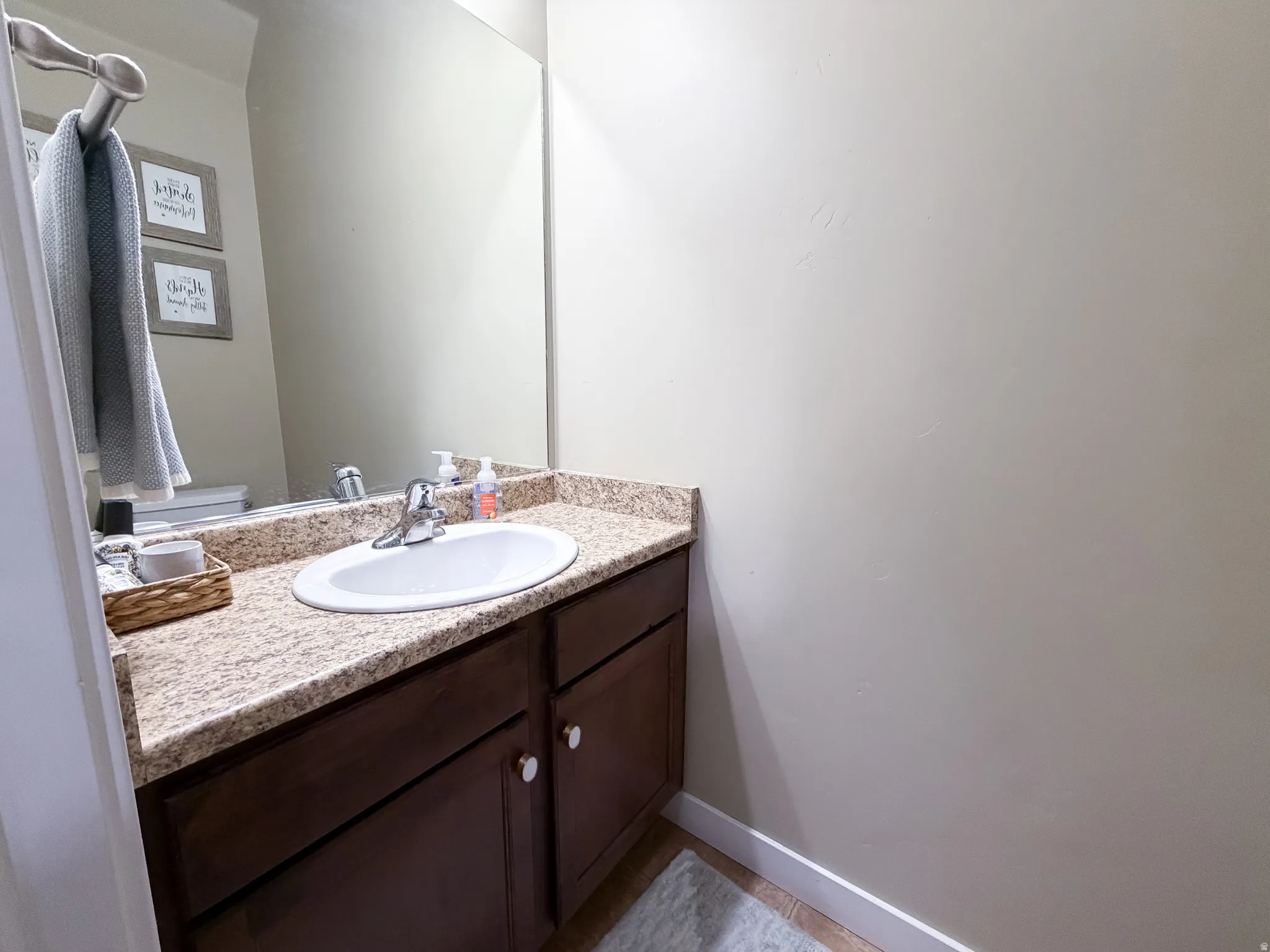 Main level bathroom with granite countertop, integrated white sink, chrome faucet, and dark wood-finish cabinetry