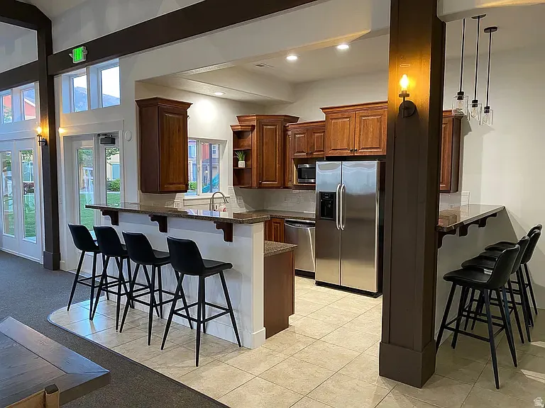 Kitchenette featuring wood-finish cabinetry, stainless steel appliances, granite countertops, and tile flooring
